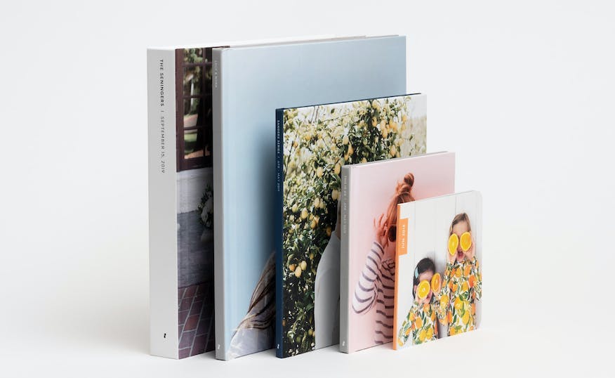 stack of hardcover and softcover photo books showing a family